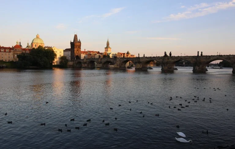 Karlův most a pražské panorama nad hladinou Vltavy.