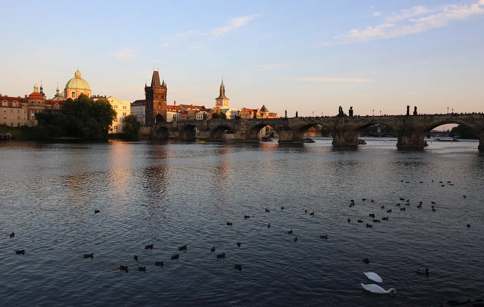 Karlův most a pražské panorama nad hladinou Vltavy.