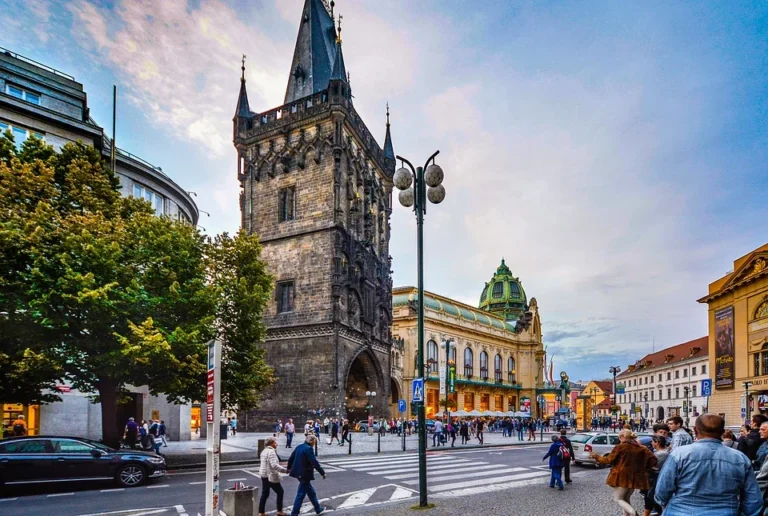 Pražská ulice s historickou věží jako pozvánka na městskou procházku.