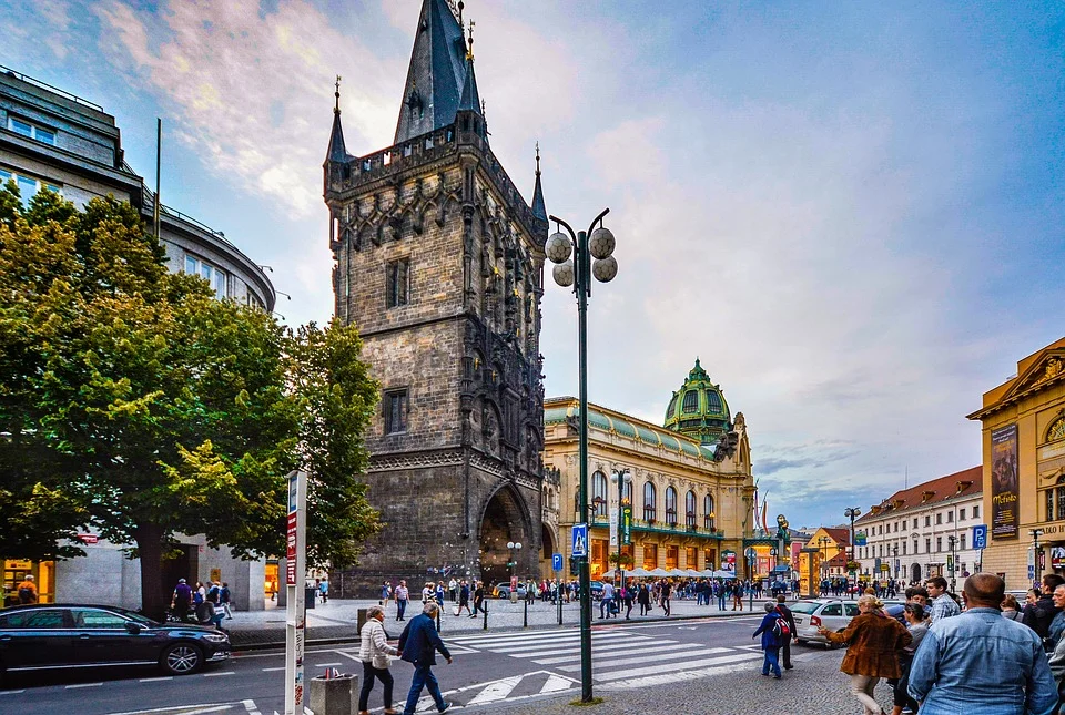 Pražská ulice s historickou věží jako pozvánka na městskou procházku.