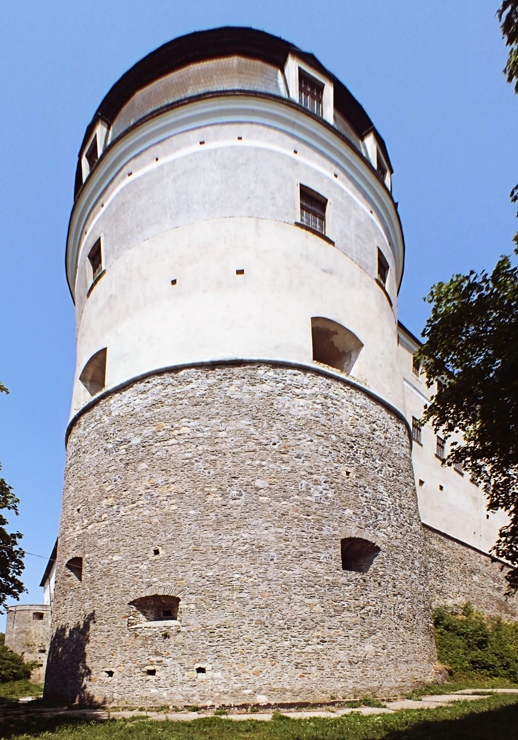 Bílá válcová věž hradu Červený Kameň s kamennou spodní částí