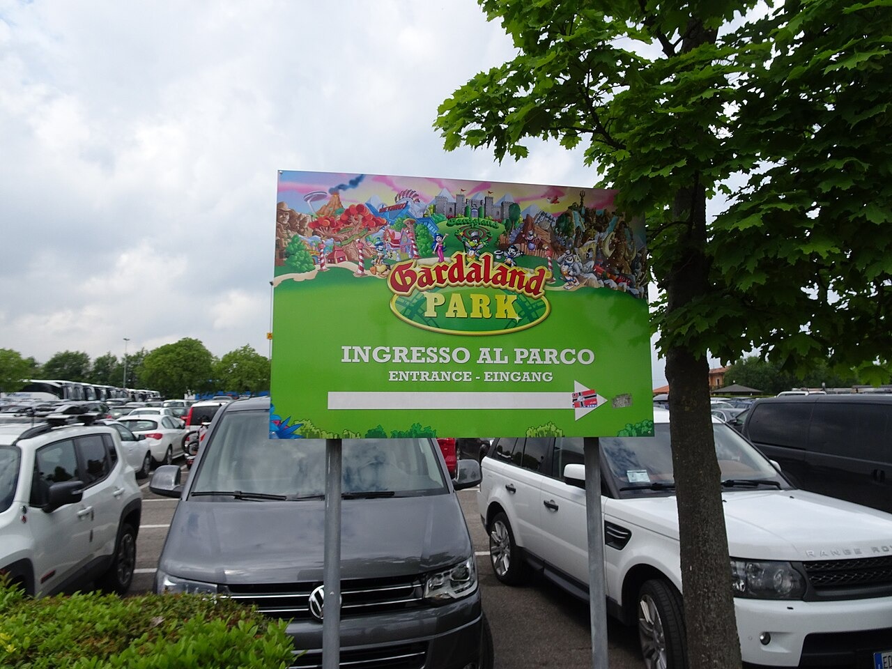 Ukazatel vstupu do parku Gardaland mezi zaparkovanými auty