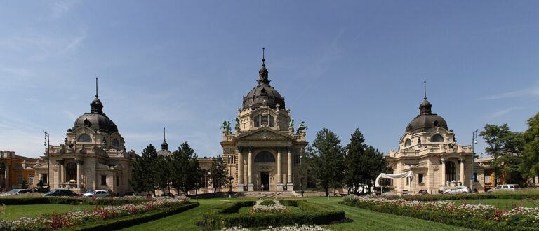 Žlutá historická fasáda a zahradní průčelí lázní Széchenyi