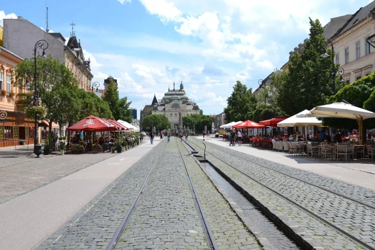 Pěší zóna na Hlavní ulici v Košicích s tramvajovými kolejemi, letními zahrádkami a budovou divadla v pozadí