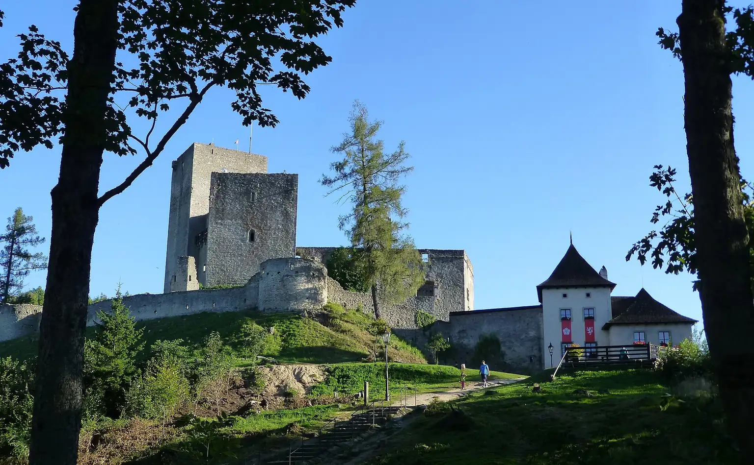 Hrad Landštejn s věží a vstupním areálem při pohledu z přístupové cesty.