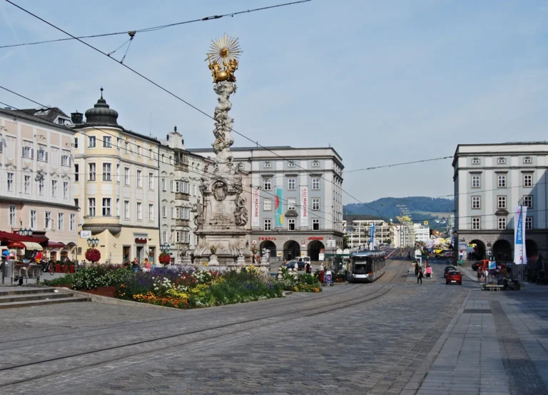 Archivní fotografie Hauptplatzu v Linci s tramvají a sloupem Nejsvětější Trojice.