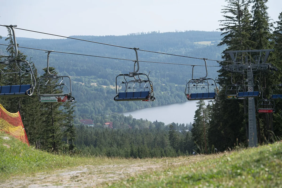 Sedačková lanovka nad sjezdovkou v areálu Lipno s výhledem na lipenské jezero, letní snímek