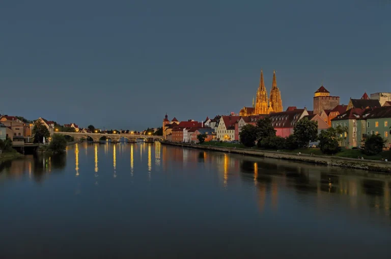 Večerní pohled přes Dunaj na Kamenný most a osvětlené věže dómu sv. Petra v Regensburgu