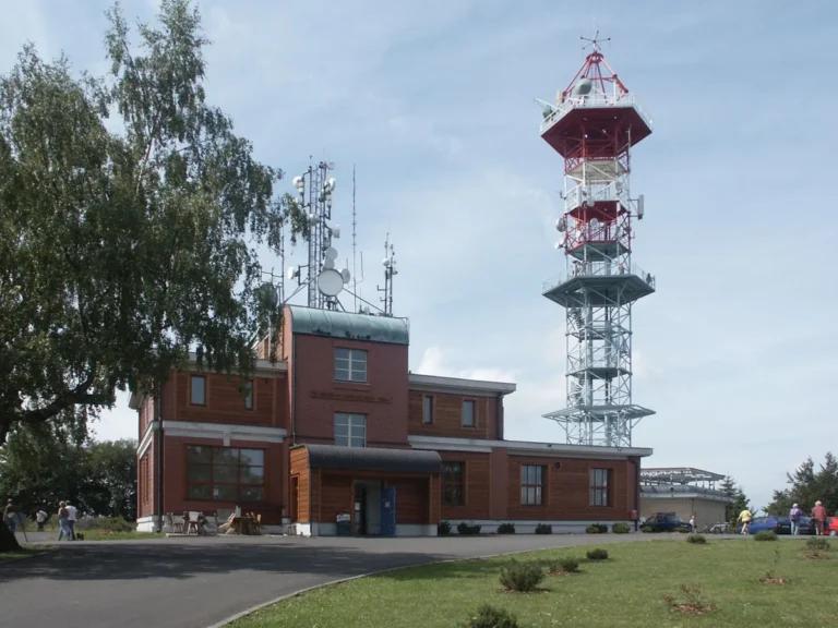 Riegrova chata na vrcholu Kozákova a za ní červenobílá kovová věž s ochozem rozhledny