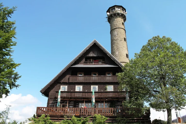 Dřevěná chata Svatobor v alpském stylu s kamennou rozhlednou na vrcholu nad Sušicí