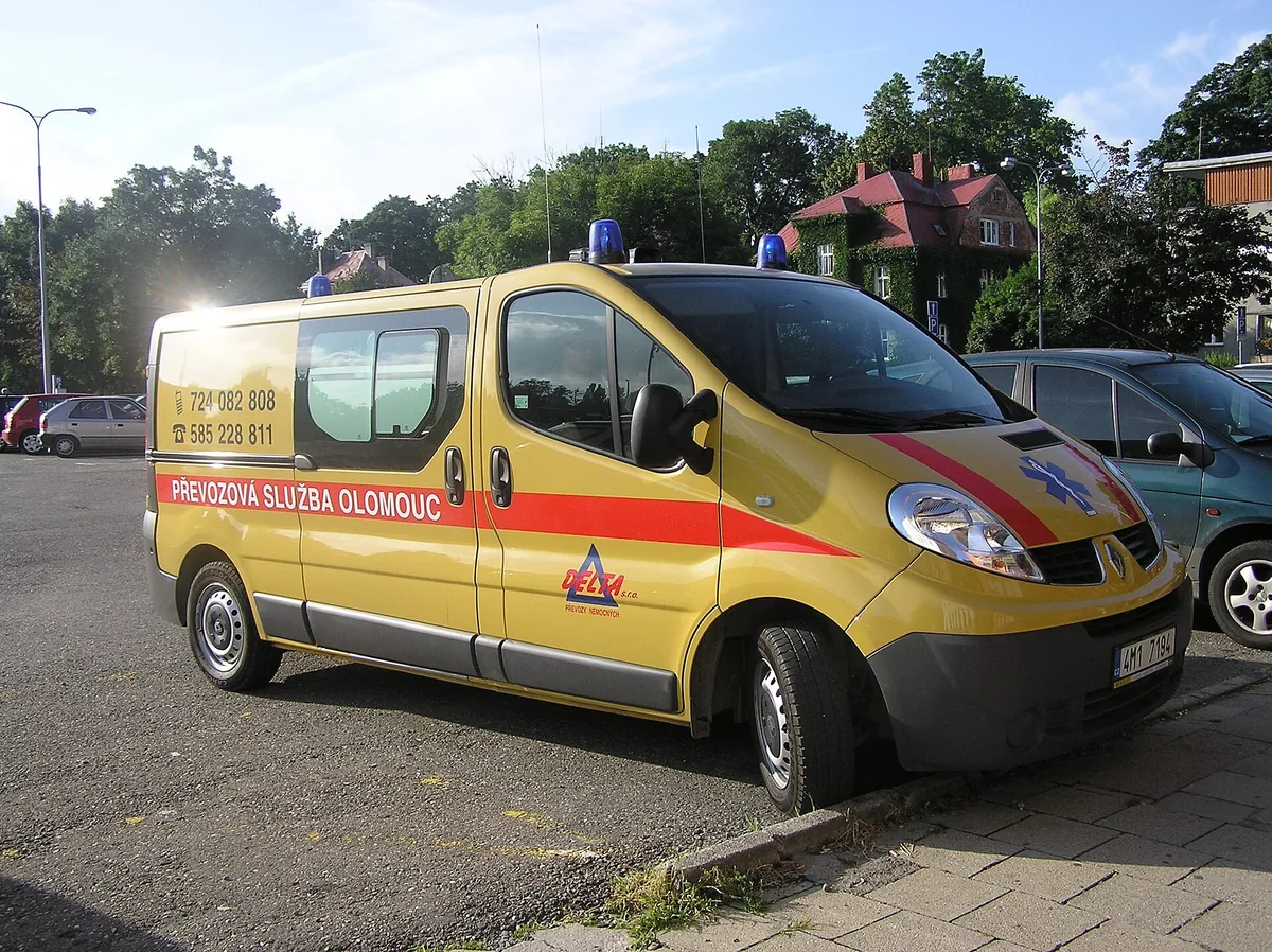 Žlutý sanitní vůz převozové služby zaparkovaný na parkovišti v Olomouci, nejde o vůz záchranné služby