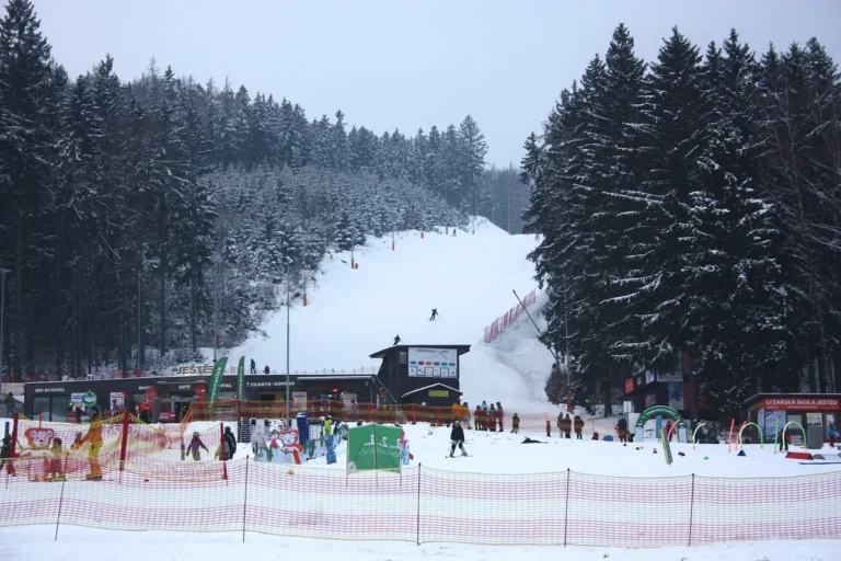 Dolní část skiareálu Ještěd v zimě s dětským parkem, lyžařskou školou a sjezdovkou