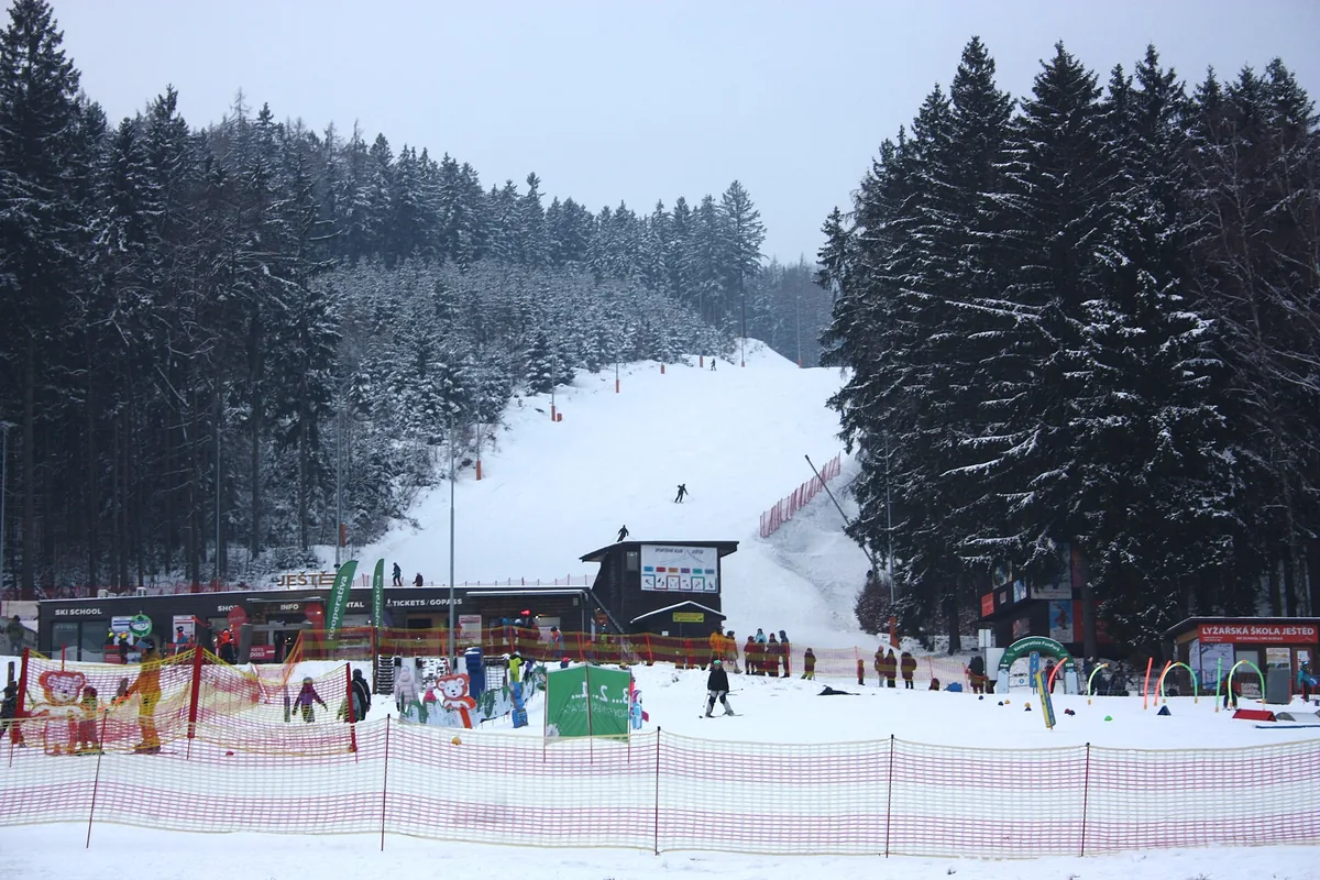 Dolní část skiareálu Ještěd v zimě s dětským parkem, lyžařskou školou a sjezdovkou