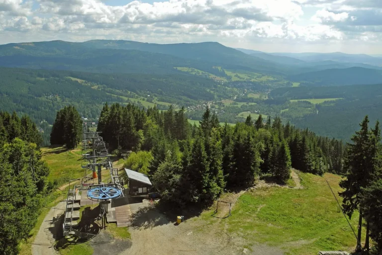 Horní stanice sedačkové lanovky na Špičáku s výhledem do údolí Železné Rudy, letní snímek