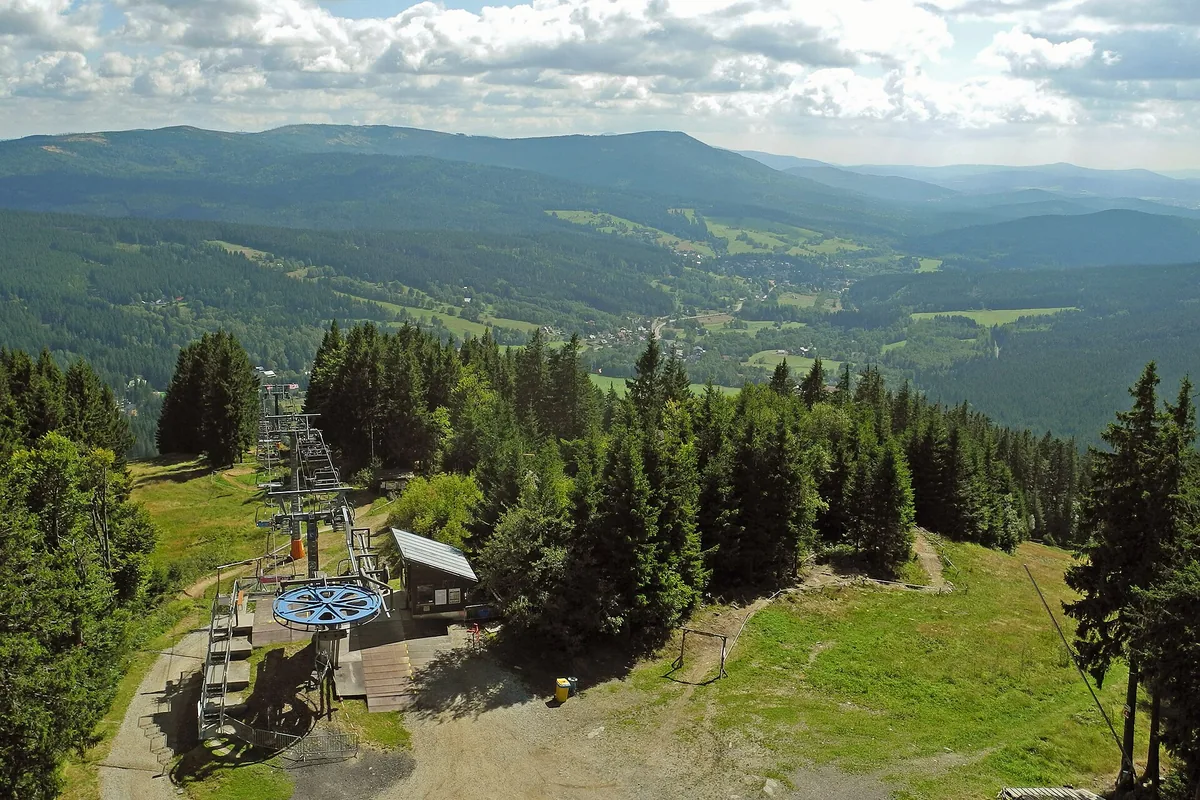 Horní stanice sedačkové lanovky na Špičáku s výhledem do údolí Železné Rudy, letní snímek