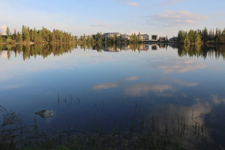Štrbské pleso s odrazem hotelů a okolního lesa na hladině
