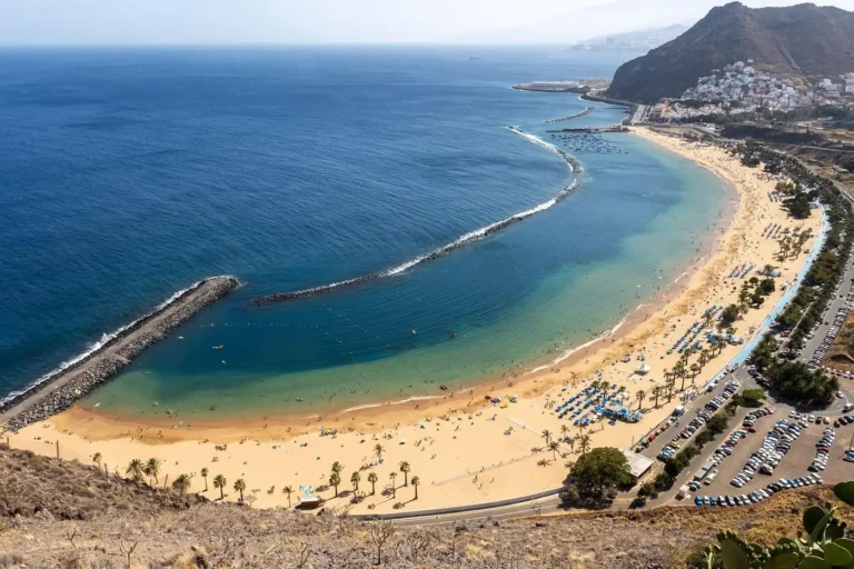 Pohled z vyhlídky na písečnou pláž Las Teresitas, ochranný vlnolam a pobřeží Tenerife.