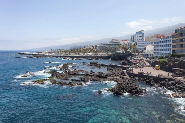 Skalnaté pobřeží Puerto de la Cruz s promenádou a městskými domy na severu Tenerife.