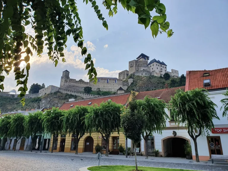 Trenčianský hrad na skále nad domy a stromy Mírového náměstí v Trenčíně