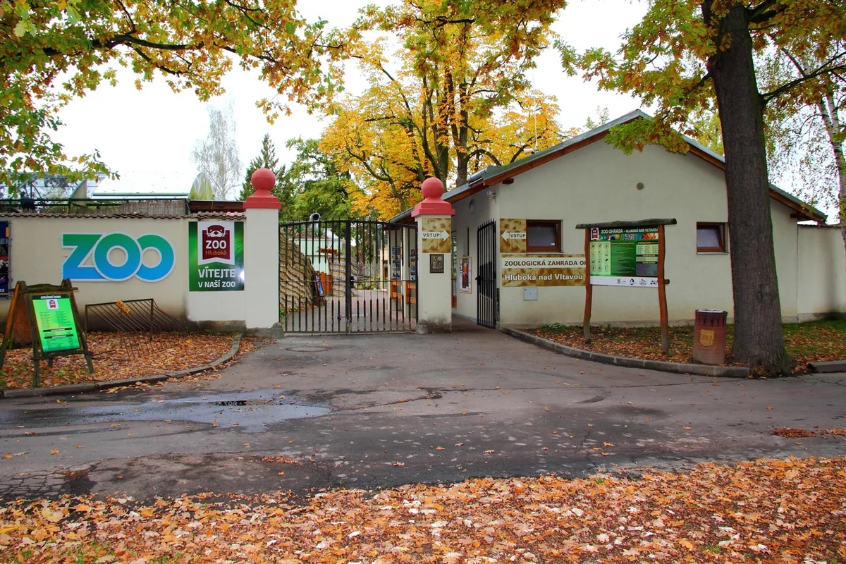 Vstupní brána Zoo Hluboká s nápisem ZOO a pokladnou pod podzimními stromy