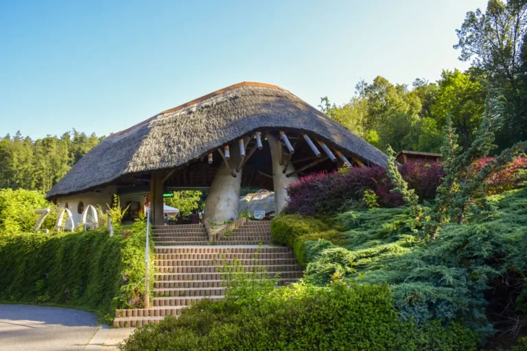 Hlavní vstup Zoo Jihlava s doškovou střechou a okolní zelení.