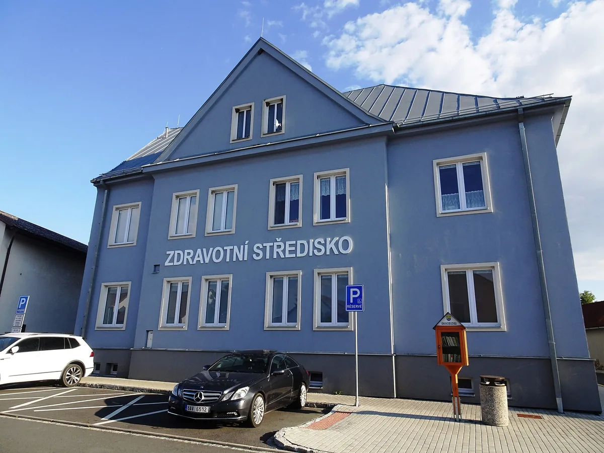 Modrá budova zdravotního střediska v Holýšově s nápisem na fasádě, snímek ze srpna 2022