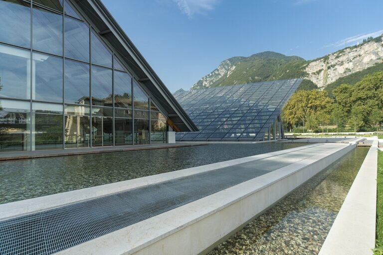 Moderní prosklená budova MUSE Trento u vodní plochy