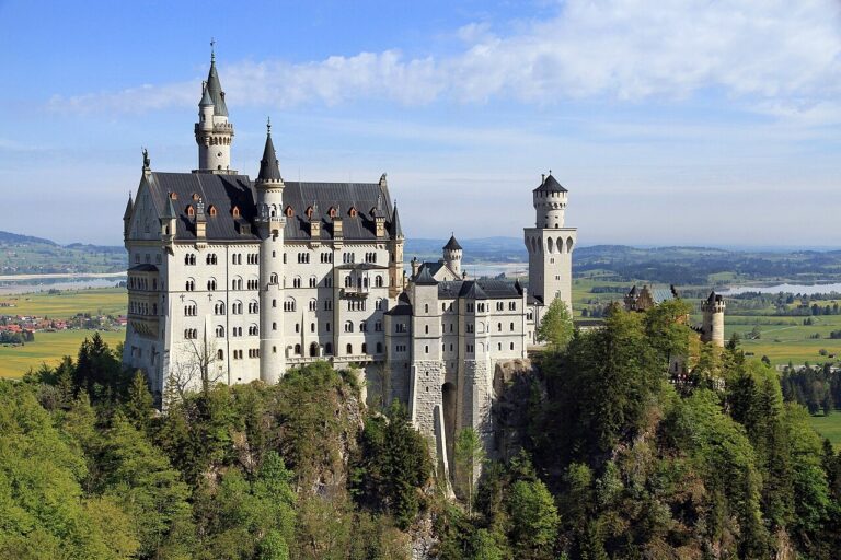 Bílý zámek Neuschwanstein nad lesem při pohledu od Marienbrücke