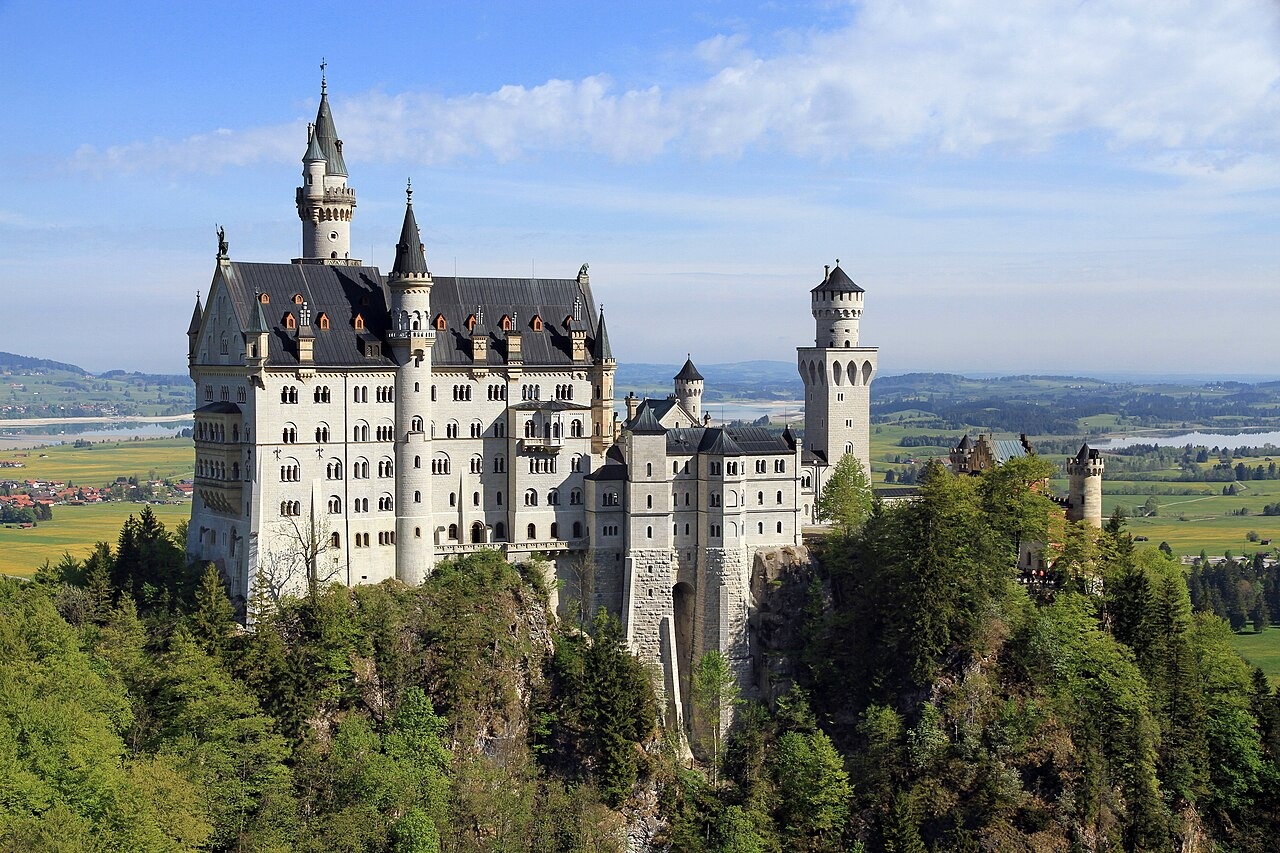 Bílý zámek Neuschwanstein nad lesem při pohledu od Marienbrücke