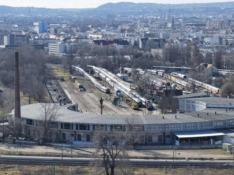 Pohled na lokomotivy, kolejiště a budovu železničního parku Budapešť
